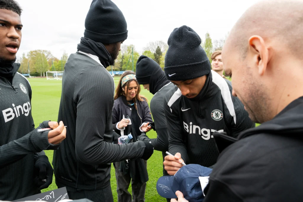Chelsea FC players in BingX training kit signing autographs for VIPs at Cobham 